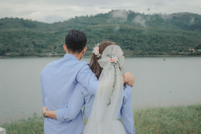 Rear view of couple standing by lake