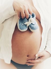 Midsection of woman holding heart shape against white background