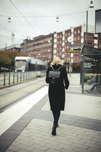 Full length rear view of businesswoman walking on tram station in city