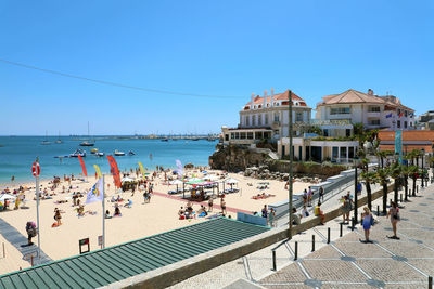 Group of people on beach by sea against clear sky