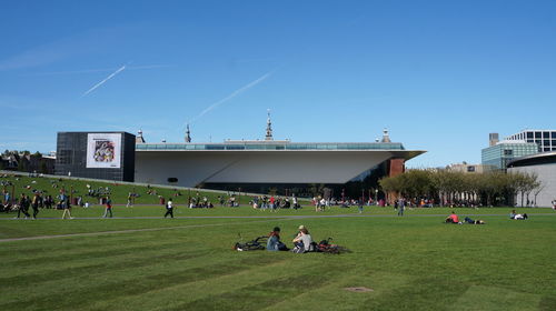 People playing soccer on field against clear blue sky