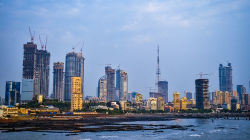 Sea by modern buildings against sky in city