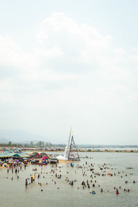 Group of people on sailboat in sea against sky