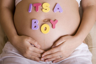 Close-up of its a boy text on pregnant woman abdomen