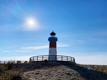 Low angle view of lighthouse by building against sky