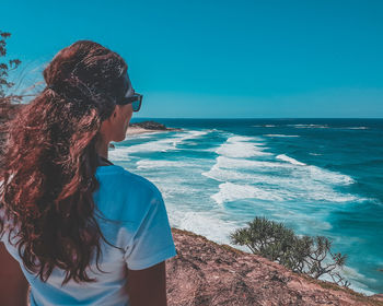 Rear view of woman standing at beach against clear sky