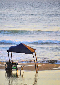 Deck chairs on beach against sky