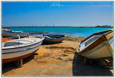 Boats moored on sea against clear blue sky