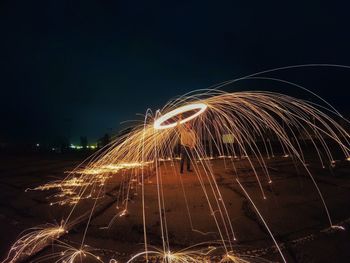 Man playing with wire wool against sky at night