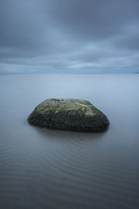 Rock on sea against sky