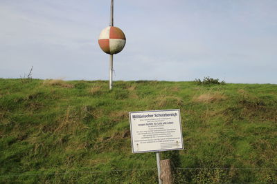 Information sign on field against sky