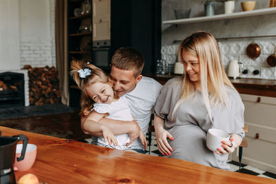 A happy family with a child having breakfast drinking tea laughing and having fun in the kitchen