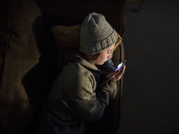 High angle view of teenage girl using mobile phone while lying on bed at home