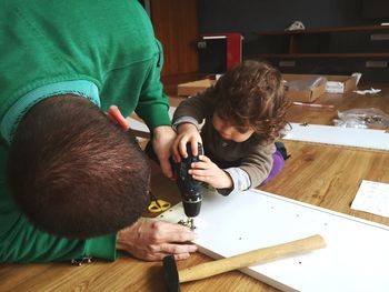 Carpenter teaching son drilling