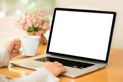 Close-up of hand holding coffee cup on table