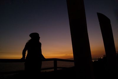 Silhouette of man on railing against sky