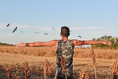 Rear view of man with arms outstretched standing on land