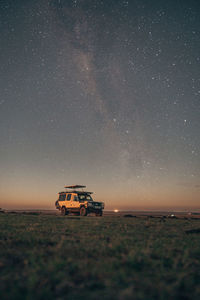 Tractor on field against sky at night