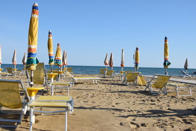 Chairs on beach against clear sky