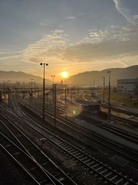 Railroad tracks in city against sky during sunset