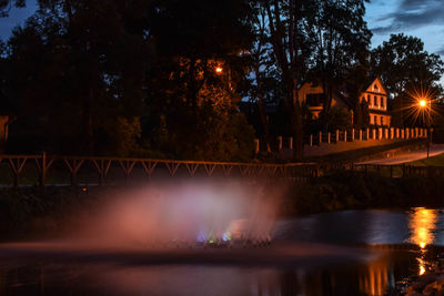 Illuminated bridge over river against sky at night