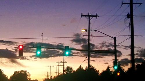 Low angle view of electricity pylon against sky at sunset