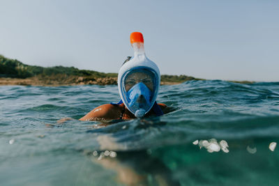 Man swimming in sea against sky