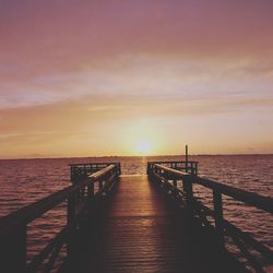 Pier over sea against sky during sunset