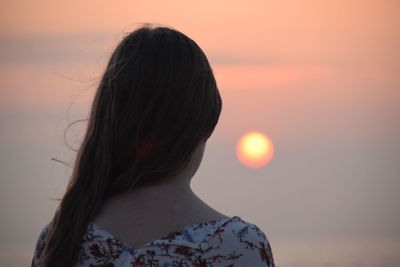 Rear view of woman against sky during sunset