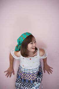 Smiling young woman standing against wall
