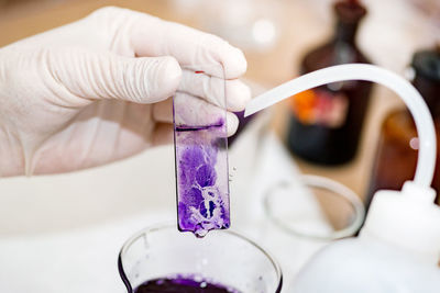 Cropped hand examining chemical on slide in laboratory