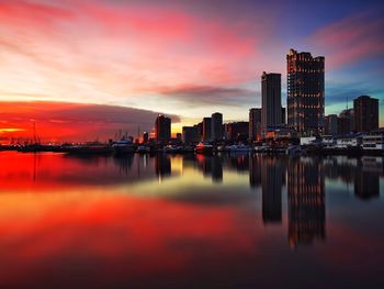 Scenic view of sea by buildings against sky during sunset