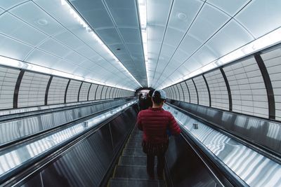 Rear view of woman on escalator at subway station