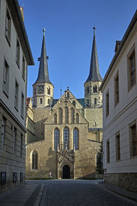 Street amidst buildings against clear blue sky