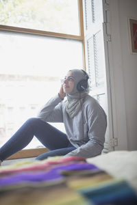 Portrait of young woman sitting on book at home