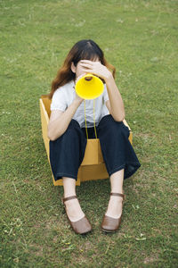 Full length of woman sitting in cardboard box