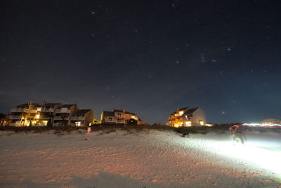 Illuminated houses against sky at night during winter