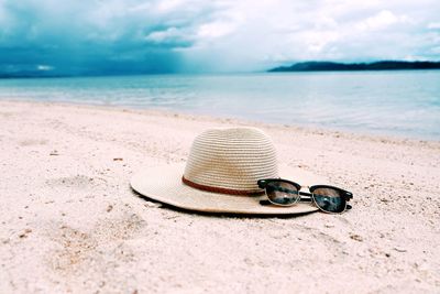 Shoes on sand at beach against sky