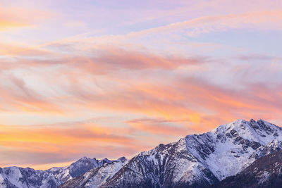 Scenic view of snowcapped mountains against orange sky