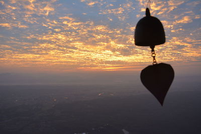 Silhouette hanging light against sky during sunset