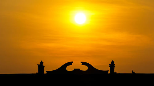 Silhouette statue against orange sky