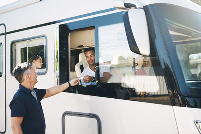 Senior man giving ticket to male in motor home while entering at trailer park