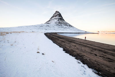 Scenic view of snowcapped mountains by sea against sky during sunset