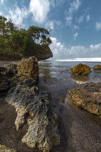 Scenic view of beach with blue sky and stone foreground
