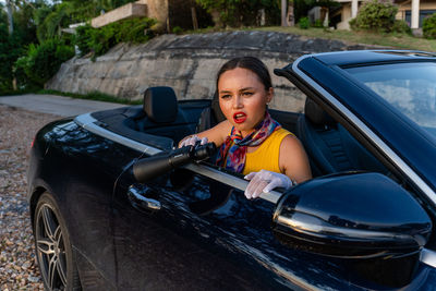 Portrait of an emotional young woman sitting in a convertible
