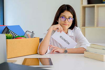 Woman with resignation text sitting at desk in office