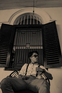 Low angle view of man sitting against building