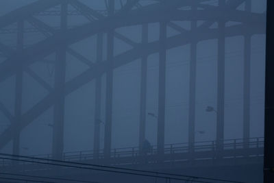 Bridge over road against sky during foggy weather
