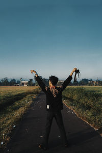 Full length of man standing on field against clear sky