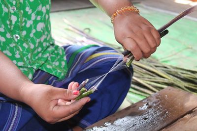 Midsection of woman extracting and weaving lotus fibers